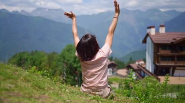 Arkadan bak. Bir kadın, dağ manzarasına el sallıyor.