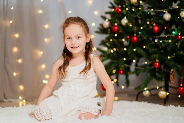 크리스마스 트리에서 하얀 드레스를 입은 행복 한 소녀. — 스톡 사진