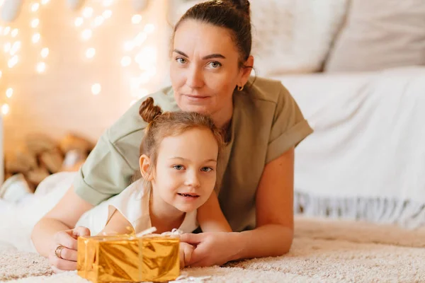 Mutter und kleine Tochter im weißen Kleid mit Geschenk in goldenem Geschenkpapier — Stockfoto