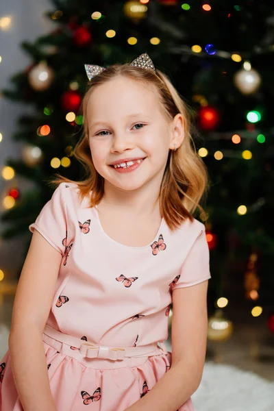 크리스마스 트리에서 분홍색 드레스를 입은 아름답고 행복 한 금발의 소녀. — 스톡 사진