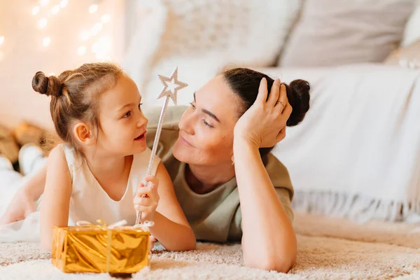 Mutter und lustiges kleines Mädchen im weißen Kleid mit Geschenk in goldenem Geschenkpapier — Stockfoto
