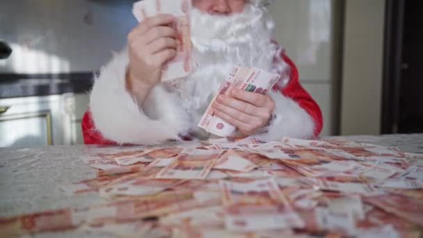Санта Клаус медленно считает деньги дома на кухне — стоковое видео