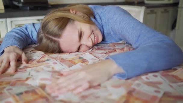 Une femme allongée dans l'argent sur la table à la maison — Video
