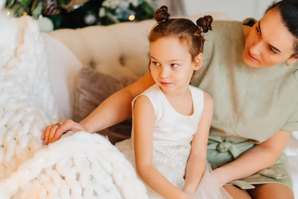 Ein süßes kleines Mädchen mit ihrer Mutter auf der Couch schaut weg. — Stockfoto