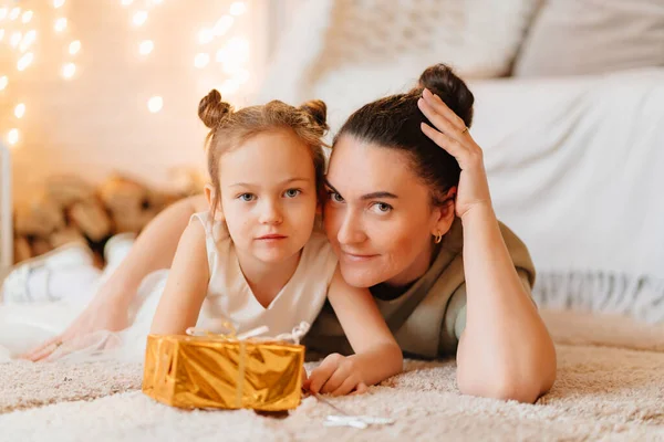 Mutter und lustiges kleines Mädchen im weißen Kleid mit Geschenk in goldenem Geschenkpapier — Stockfoto