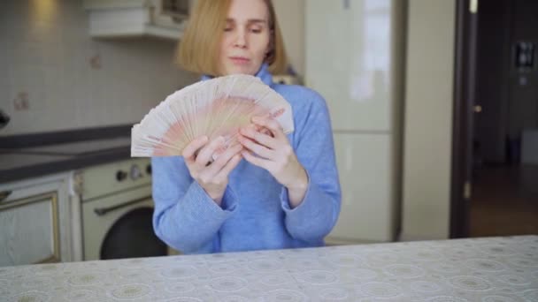 Una mujer hace un ventilador de una gran pila de rublos en casa en la cocina. — Vídeos de Stock