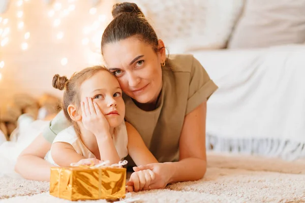 Mutter und Tochter im weißen Kleid mit Geschenk in goldenem Geschenkpapier — Stockfoto