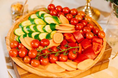 Domates, salatalık, tatlı biber ve havuç yuvarlak ahşap bir tabakta.. 