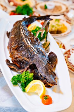 Tüm mersin balığını limon, domates ve otlarla birlikte beyaz bir tabakta pişirdim.. 