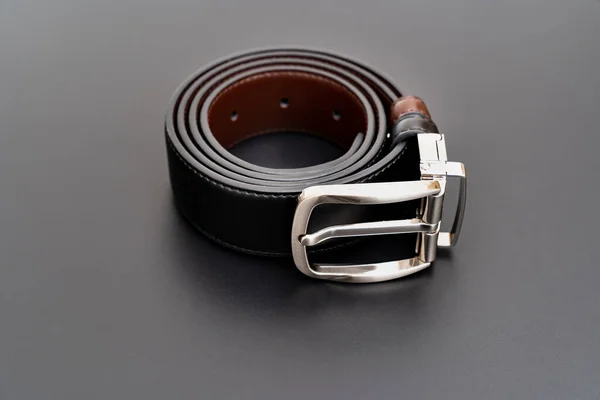 Doppelseitiger schwarzer und brauner Ledergürtel mit aufgeknöpfter Schnalle an einem schwarzen. — Stockfoto