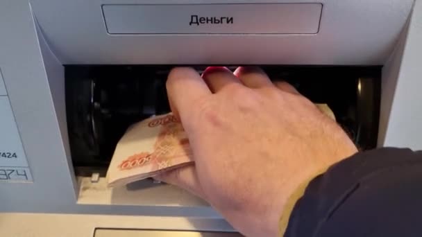 Una mano de hombre coloca billetes en un receptor de cajero automático. 5000.. — Vídeo de stock