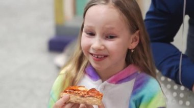 Sarışın kız bir dilim pizza yiyor. Geleneksel ve lezzetli bir yemek.