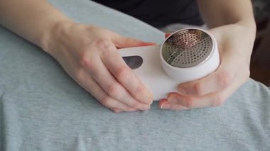 Kadın, mavi tişörtten saçma çıkarmak için bir makine kullandıktan sonra parçalara ayrılır.