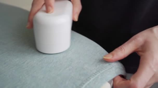 Vrouw maakt gebruik van een machine voor het verwijderen van pellet uit blauw t-shirt. — Stockvideo