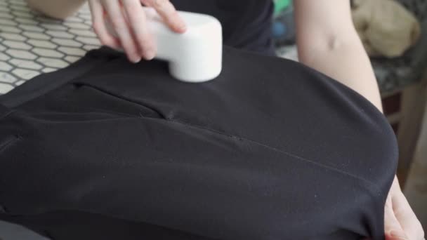 Vrouw maakt gebruik van een machine voor het verwijderen van pellet uit zwarte stof. — Stockvideo