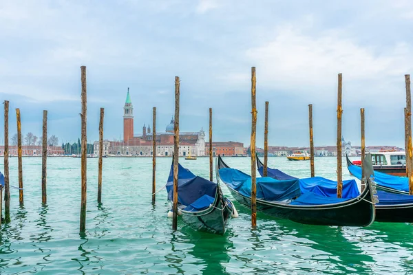 2 Aralık 2021 - Venedik, İtalya: Gondollar arka planda Chiesa di San Giorgio Maggiore ile Grand Canal 'daki Sam Marco Gondola Servis İstasyonu' na demirlediler.