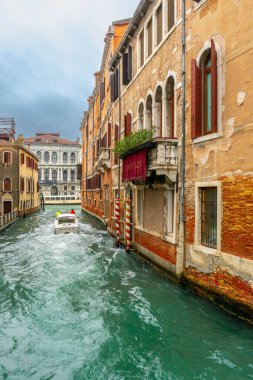  İtalya, Venedik 'teki evler arasında dar kanal boyunca seyreden bir motorlu tekne..