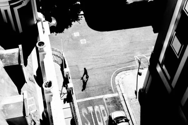 high contrast black and white image of pedestrians crossing the road from an elevated view