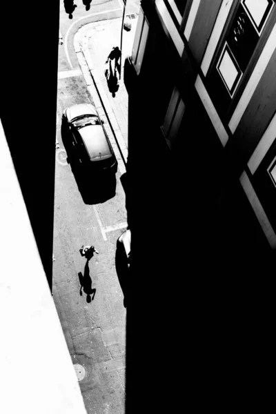 high contrast black and white image of pedestrians crossing the road from an elevated view