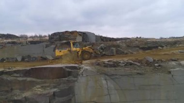 Granit ocağının hava manzarası, granit parçaları toplayan büyük traktör, büyük taşlar, granit kaplama madencilik. Doğal minerallerin çıkarılması.