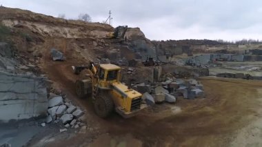 Granit ocağının hava manzarası, granit parçaları toplayan büyük traktör, büyük taşlar, granit kaplama madencilik. Doğal minerallerin çıkarılması.