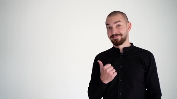 自信に満ちた若い髭の男が左を指差して親指を立てている — ストック動画