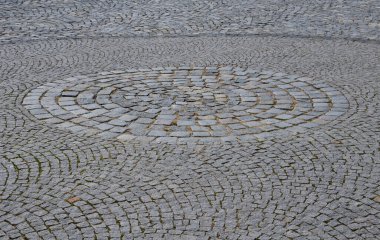 Küçük bir parke küpünün içinde büyük, koyu gri bir daire olan kare. Taş granit ve bazalt. Şehrin tarihi merkezinde arabaların ve limuzinlerin döndüğü bir onur mahkemesi.