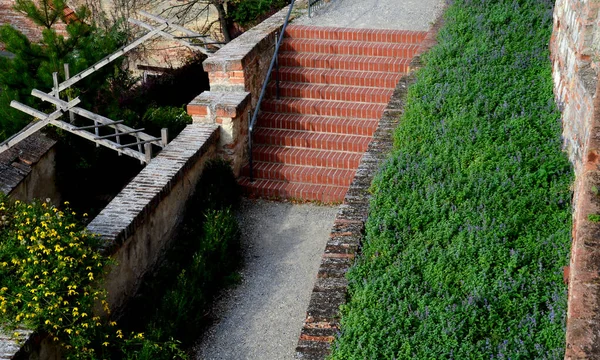 park staircase on the terrace of an Italian garden. the stairs are made of red bricks glued to cement. forged metal railing on the retaining wall