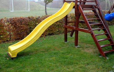 Hornbeam çitleri ve sonbahar sisiyle çevrili oyun parkı. Salıncaklı ahşap yapı ve plastik sarı kaydırak, hepsi ev yapımı. Merdivenlerde ya da merdivenlerde tırabzan olan kuleye çıkıyor.