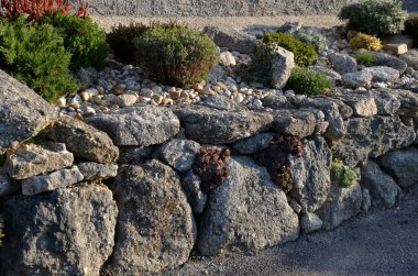 dry gray wall, folded boulders without the use of cement. the art of folded retaining walls. very colorful rock gardens like the rocky environment. garden architecture clipart