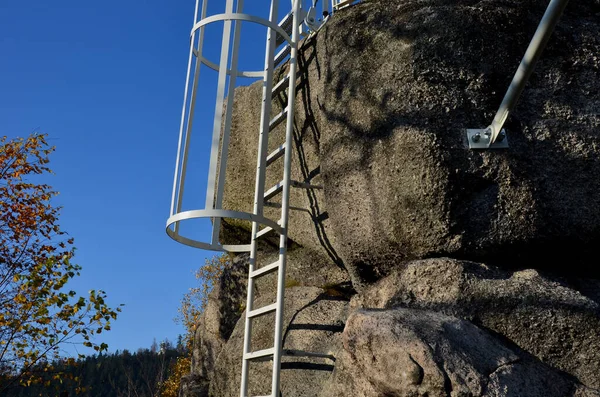 galvanized iron gray fire ladder leading to the rock. safety is ensured by a tube-shaped grille of the protective grille. people climb up the blue sky. mountaineering climbing route with via ferata