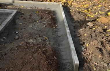 Asfalt inşaatı, temel beton kaldırımlar. İnşaat kazıcısı. İnşaatçılar yeni sokak yüzeyleri yapıyorlar. Fayanslar çakıl döşenecek. Sonbahar çalışma alanı. Kepçele, tekerlekler