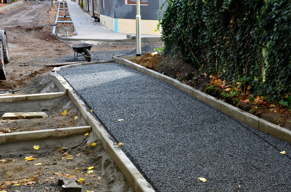 Строительство тротуаров, укладка бетонных бордюров в фундамент. строительный экскаватор. строители создают новые уличные поверхности. плитки будут уложены в гравий. Осеннее рабочее пространство. самокат, колеса