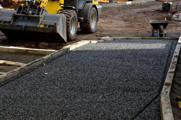 Строительство тротуаров, укладка бетонных бордюров в фундамент. строительный экскаватор. строители создают новые уличные поверхности. плитки будут уложены в гравий. Осеннее рабочее пространство. самокат, колеса