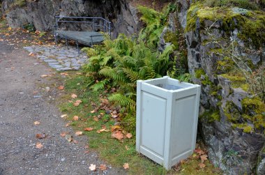 Bahçe evi yatay kalaslarla kaplı. Yeşil bir çatının tepesinde, bitkiler ve eğreltiotları tırmanıyor. Açık mavi banklar ve parktaki ahşap çöp kutusu, saunalı bahçe, gizli bahçe kulübesi.