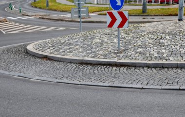 Merkeze yakın eğimli bir pervazda gri granit küplerin kaldırım taşları. Çemberin ortasında asfalt ve yön okları olan beton kaldırımlar, ulaşım bağlantıları.