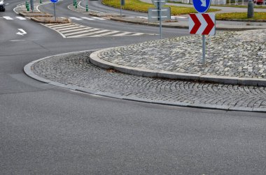 Merkeze yakın eğimli bir pervazda gri granit küplerin kaldırım taşları. Çemberin ortasında asfalt ve yön okları olan beton kaldırımlar, ulaşım bağlantıları.