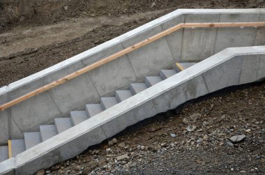 Sapının altından sarı ışıklı bir LED şerit çıkıyor. Gizli lamba bir adamın elini gösteriyor. Merdivenin beton tarafı, istinat duvarlarıyla yokuş aşağı gidiyor.