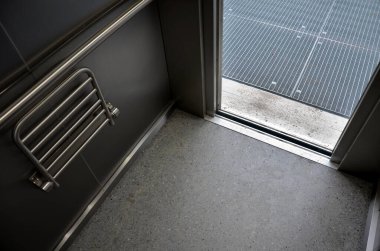 Paslanmaz çelik asansörden çıkın. Asansör katlanabilir bir koltukla donatılmıştır. Açıldığında kafesi, ağ zemini ve balkon parmaklıklarını görebilirsin..