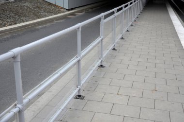 Otobüs platformu, gri metal bir boruya bağlı şeffaf pleksiglass tarafından korunuyor. İnsanlar geçen arabaların pisliğine bulanmaz.
