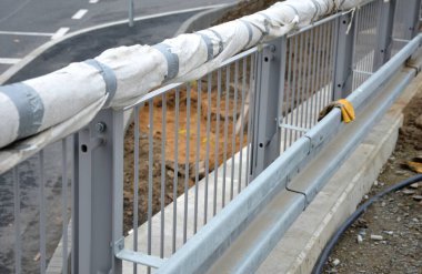 Yol bariyerleri olan korkuluklar. Köprü ya da üstgeçit üzerinde metal endüstriyel eskrim. Kapı kolu beyaz jeotextile sarılı. Yeni ve onaylanması gerekiyor.