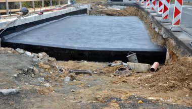 Köprünün yeniden inşası. Beton zift ziftinden su birikintilerine kadar kara ziftle kaplanmış. İnşaat alanının kenarını işaretleyen güvenli plastik işaretler