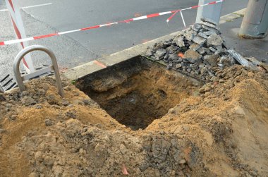 Sıcak suyu olan boruların tamiri ya da derin bir çukurdaki buhar girişten korunmak için geçici inşaat çitleriyle çevrili bir madene benzer. Kaldırıma ağaç dikiyorum.