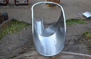 Çimenli tepeler ve ahşap çayırları olan paslanmaz çelik kaydırak. Tartan kauçuk pede çarpan kaygan çocuklar için büyük parlak bir tüp. Tüpün ucu açık bir yalaktır.