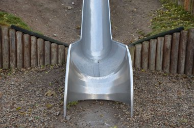 Çimenli tepeler ve ahşap çayırları olan paslanmaz çelik kaydırak. Tartan kauçuk pede çarpan kaygan çocuklar için büyük parlak bir tüp. Tüpün ucu açık bir yalaktır.