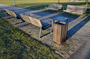 Bankların altındaki panellerdeki ahşap banklar, çiçek açan romantik çiçek tarlaları ve çimenliklerdeki ziyaretçilerin ayakkabıları tarafından kazınan beton, anti-kazıma bej yollarından oluşan bir dikdörtgen.