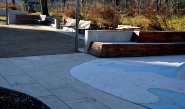 Tepeli, mavi-mavi-yeşil kauçuk manzara ve sahada renkli noktalar. Tepenin içinden paslanmaz çelik tünel. ahşap kaplanmış eğimli köşe bank istinat duvarı