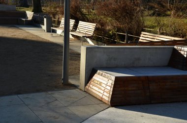 Tepeli, mavi-mavi-yeşil kauçuk manzara ve sahada renkli noktalar. Tepenin içinden paslanmaz çelik tünel. ahşap kaplanmış eğimli köşe bank istinat duvarı