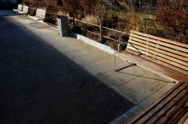 Bankların altındaki panellerdeki ahşap banklar, çiçek açan romantik çiçek tarlaları ve çimenliklerdeki ziyaretçilerin ayakkabıları tarafından kazınan beton, anti-kazıma bej yollarından oluşan bir dikdörtgen.