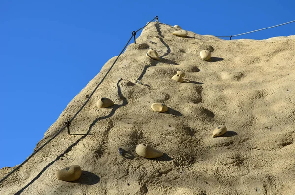 攀岩墙 由天然形状的人造石头制成 有不规则的间隔和螺丝状的石头 吊绳上用来固定攀登者的手柄和扣子 — 图库照片